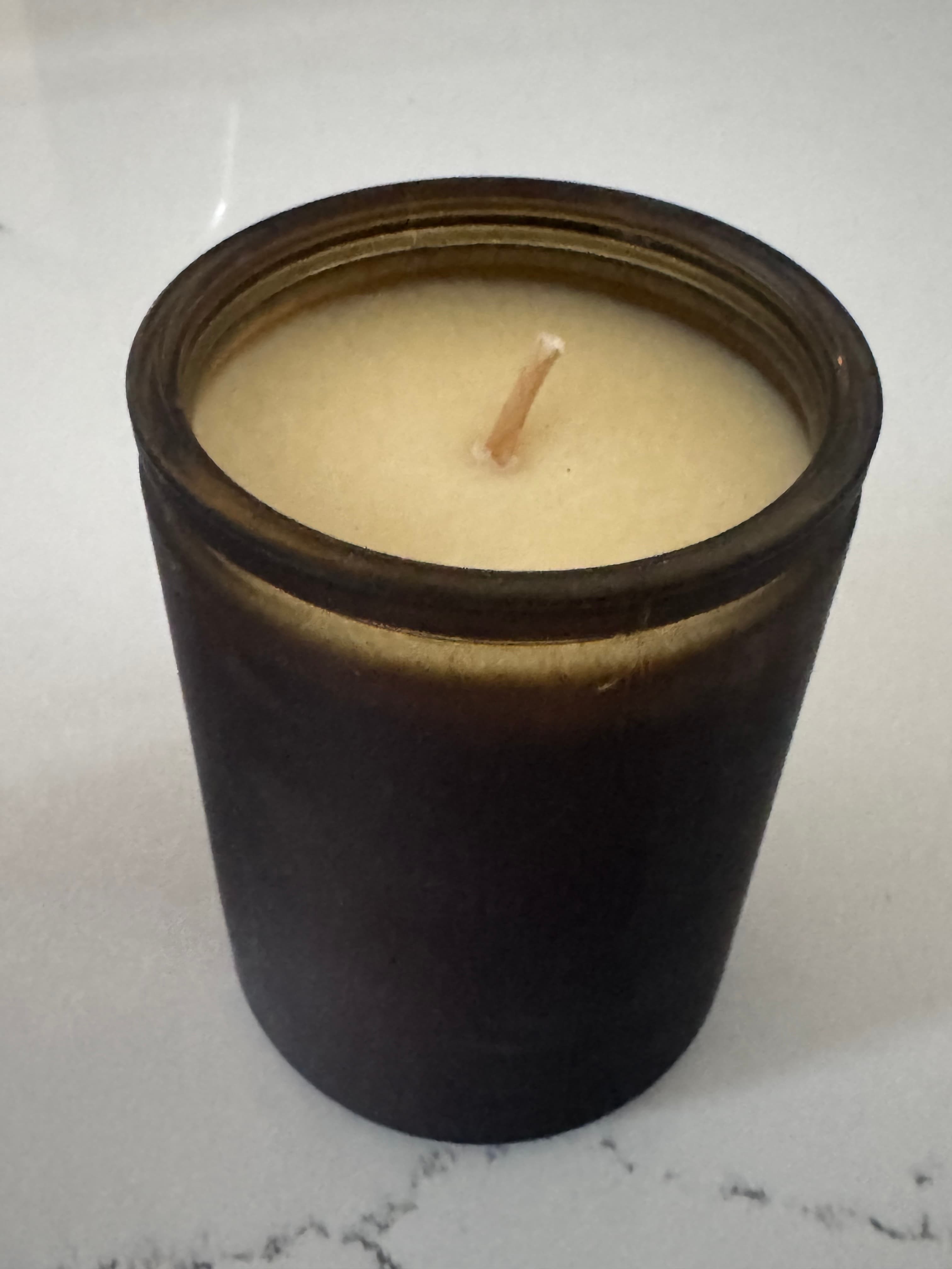 Source photo of a soy candle in an amber jar on a marble counter