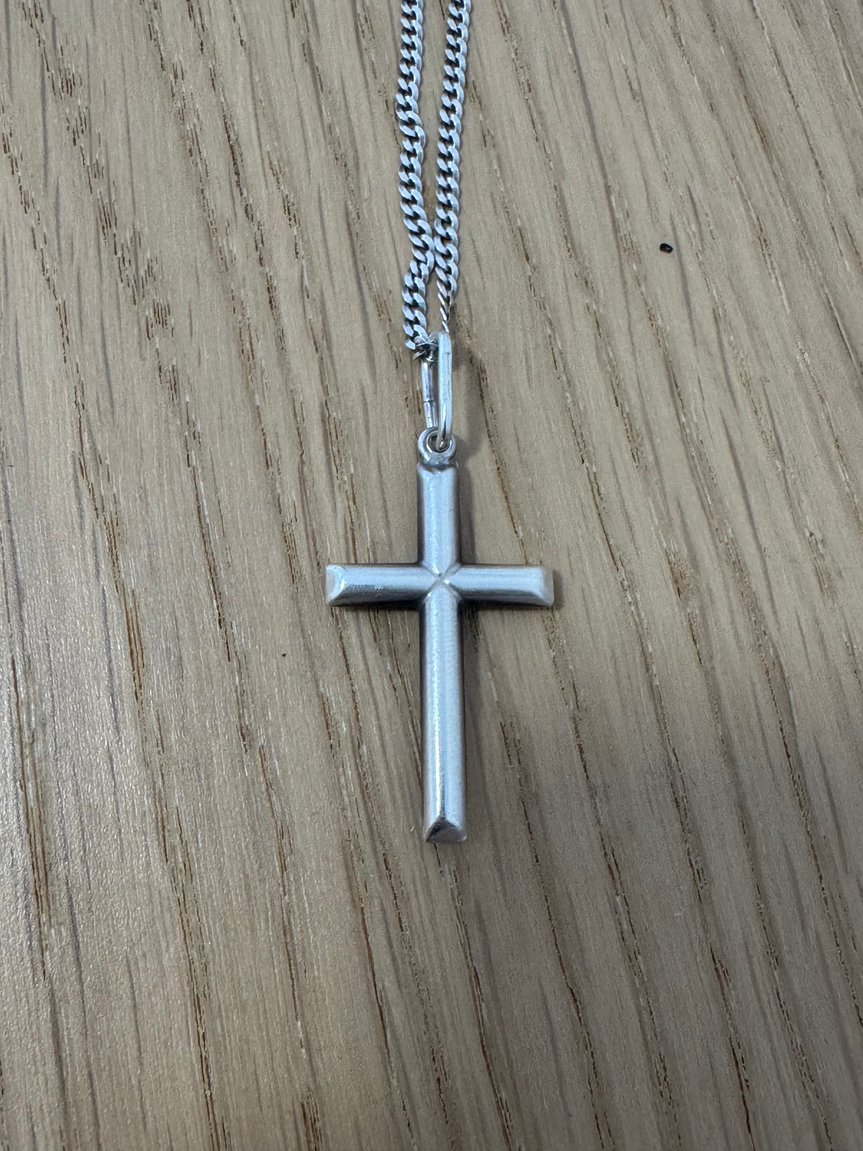 Source photo of a silver cross pendant on a wooden surface