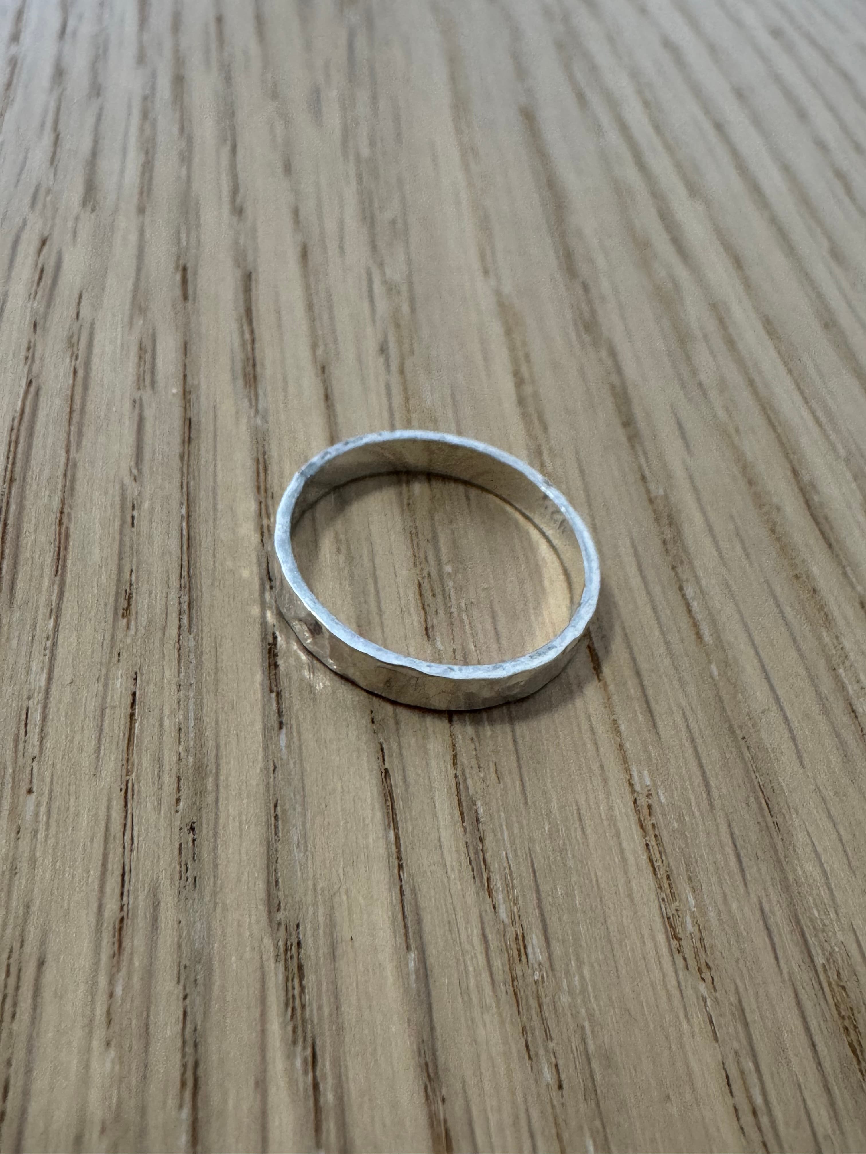 Source photo of a silver hammered ring on a wooden surface